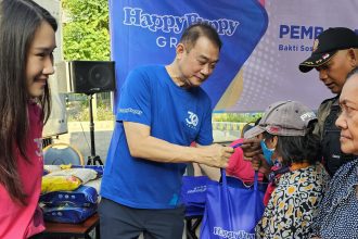Steffiani Setyadji mendampingi ayahnya, Santoso membagikan beras kepada warta sekitar lokasi outlet Happy Puppy di Jalan Dr Soetomo.